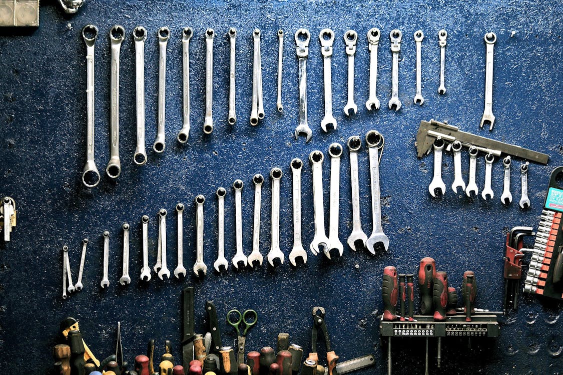 A well-organized workshop with various hand tools and wrenches hanging on a pegboard wall